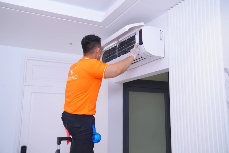 Technician in orange uniform servicing an air conditioner unit